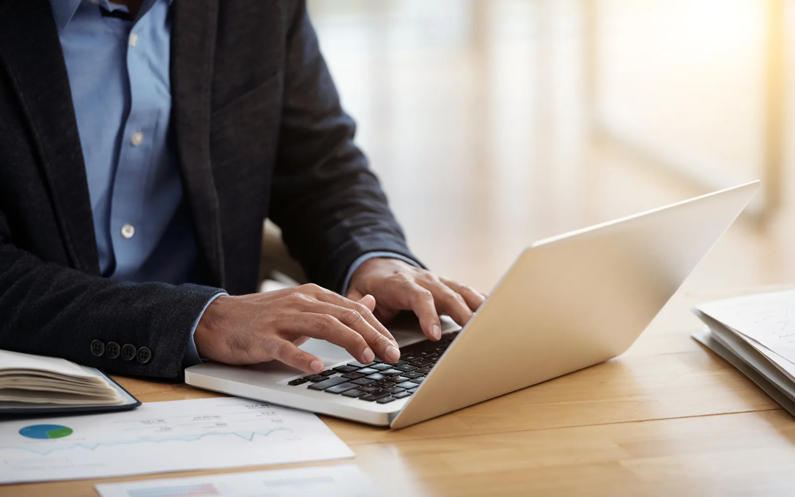 A person working through printed charts and figures beside a laptop at a desk