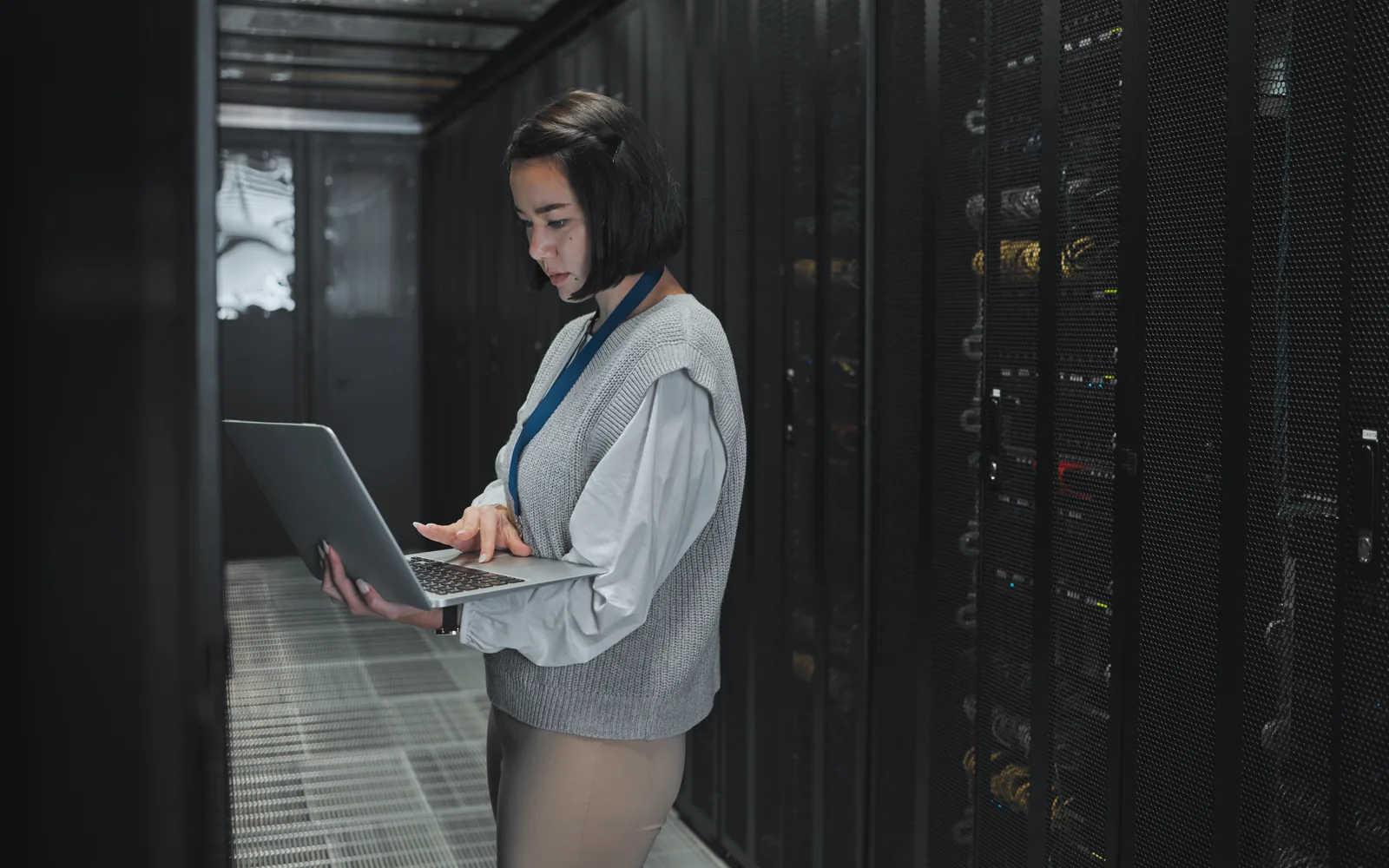 A person carrying a laptop between rows of servers in a data centre