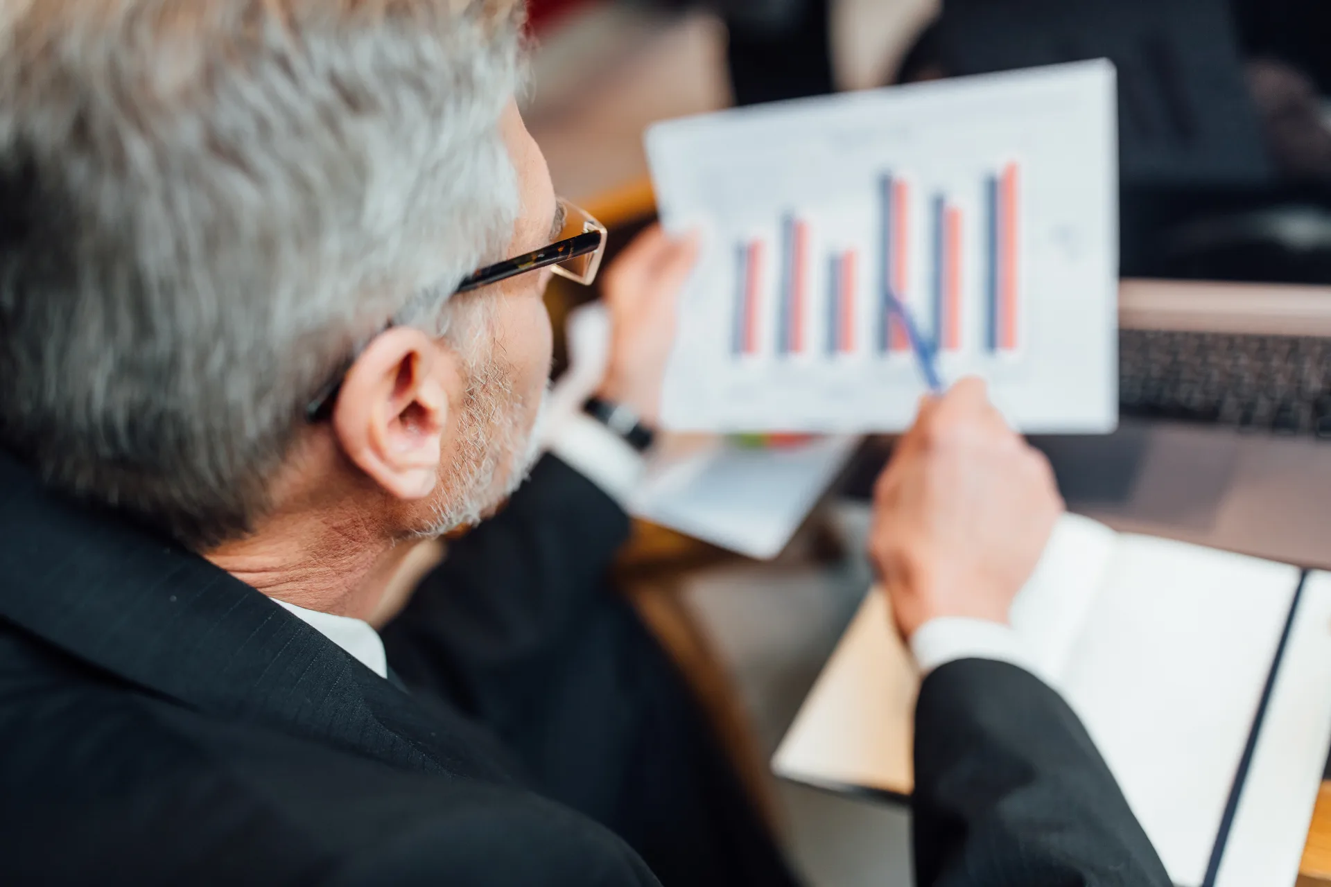 A senior finance professional reviewing a printed bar chart