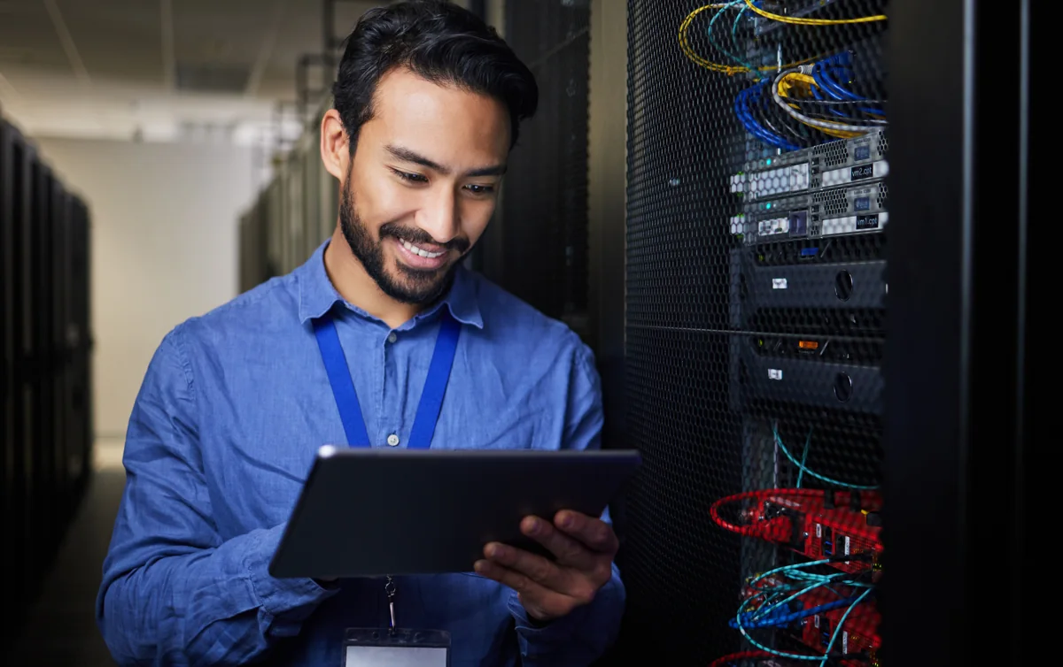 An engineer with a tablet working among server racks in a data centre